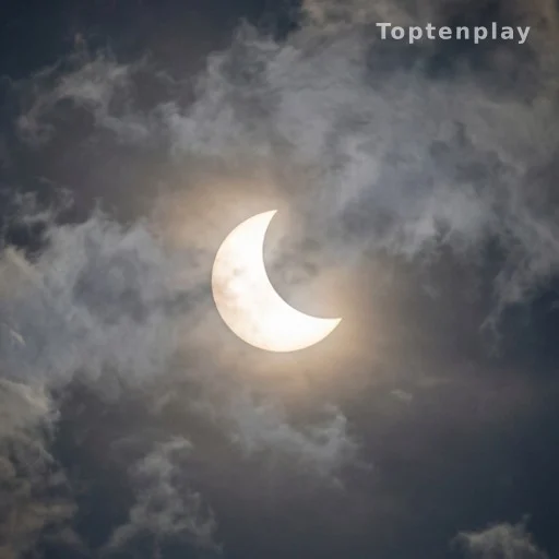 Éclipse solaire partielle visible à travers des nuages, lumière naturelle dramatique