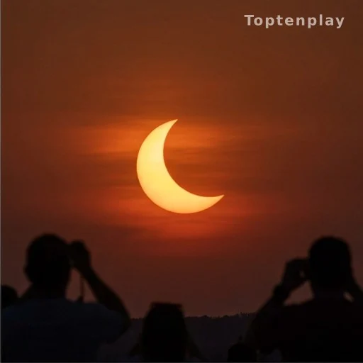 Croissant solaire rouge à l'horizon lors d'une éclipse partielle en soirée